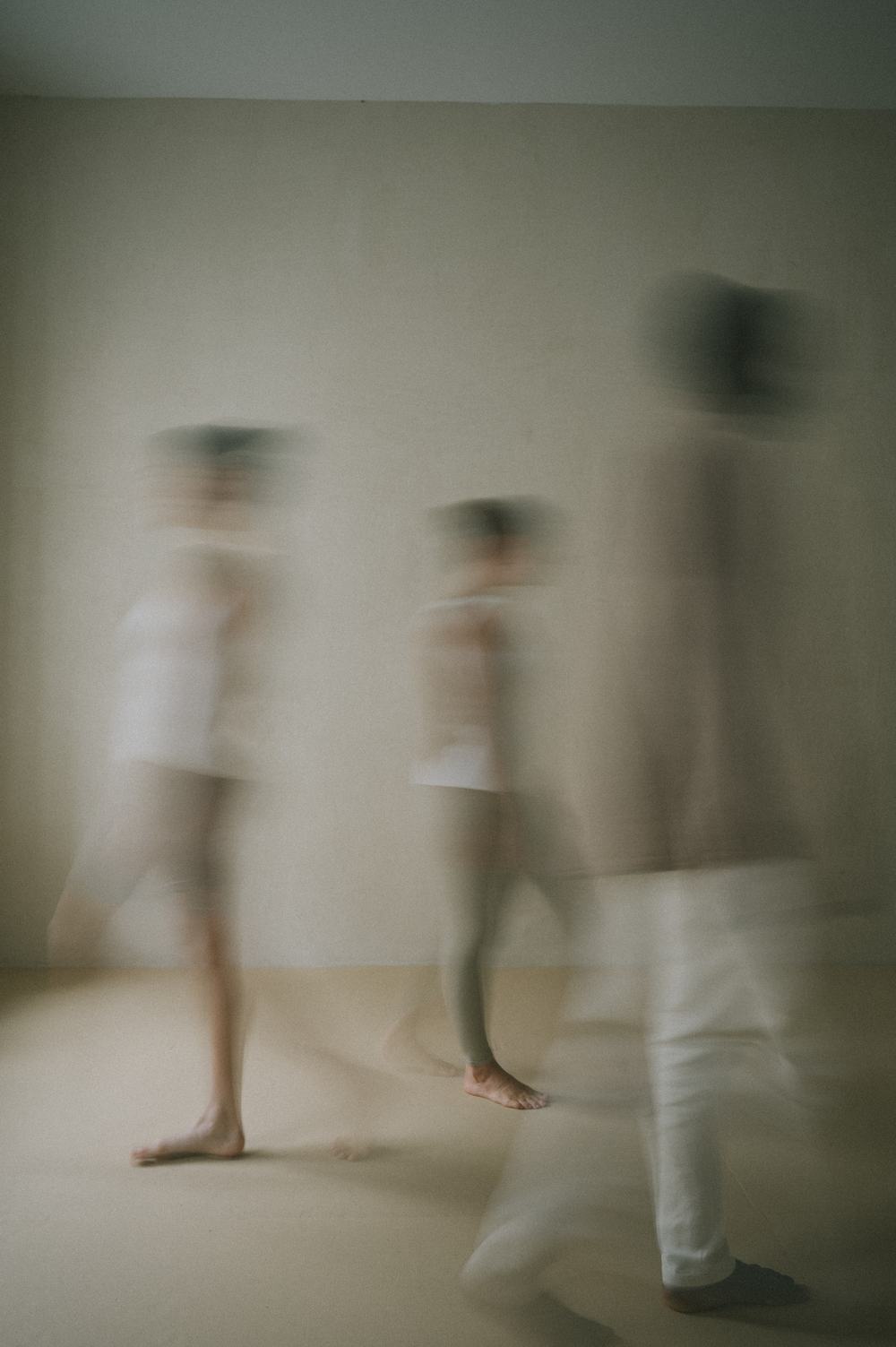 Three people moving through a bright room, softly blurred